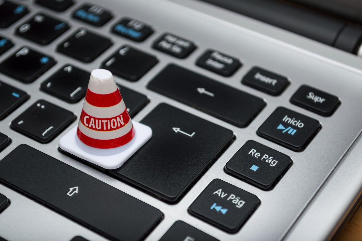 A small white caution cone resting on a computer keyboard, symbolising cybersecurity and data protection
