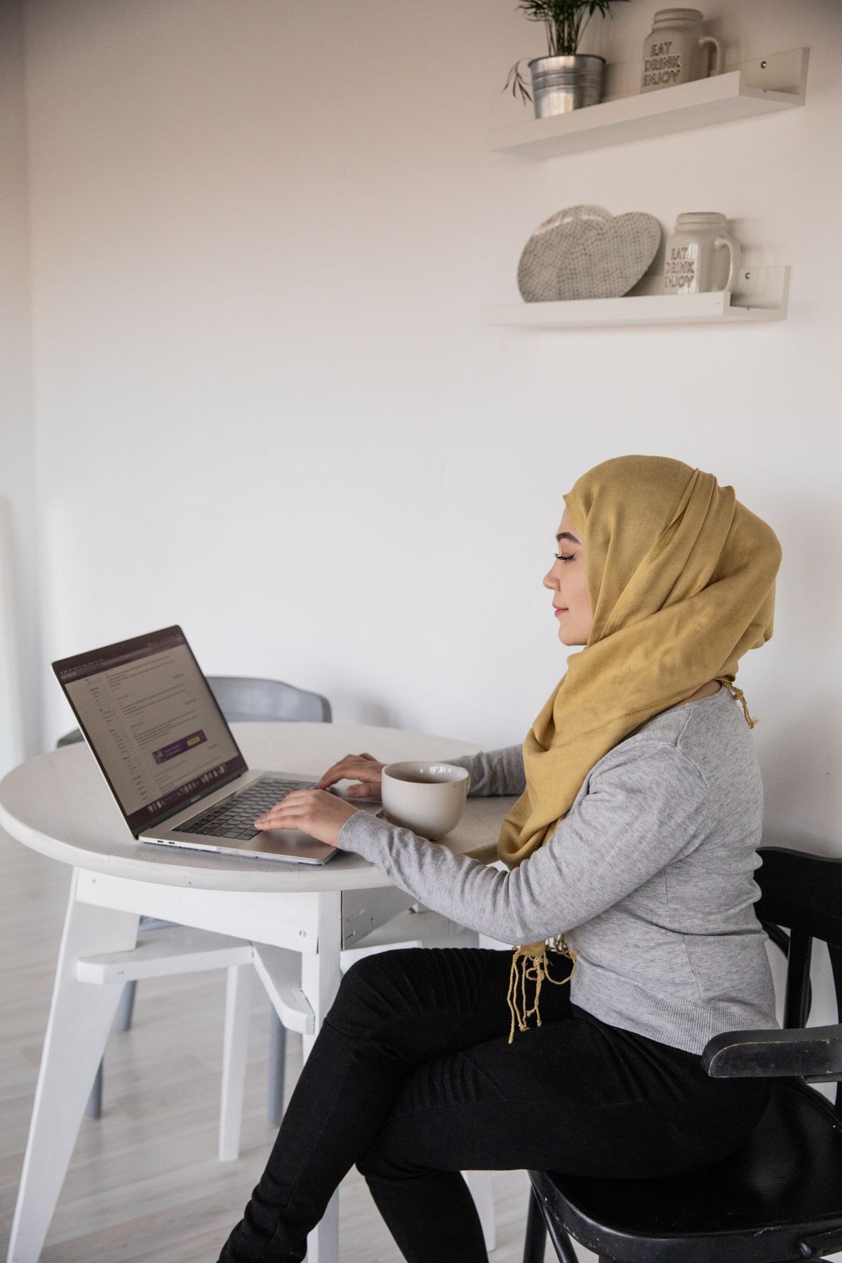 Businesswoman in a hijab working on a laptop at a desk, seen from the side