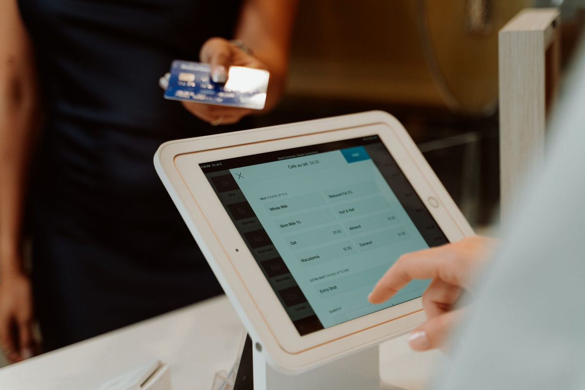 Close-up of a tablet-based ordering and card payment system at a small business counter