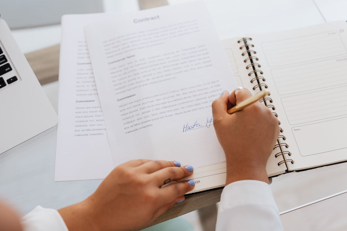 Close-up of hands signing a contract on a desk, representing a franchise agreement being signed