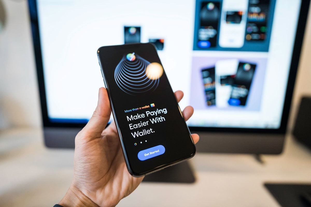Hand holding a smartphone showing a digital wallet app, representing a fintech product being tested before licensing