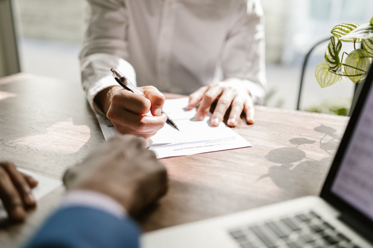 Close-up of hands signing a document at a desk
