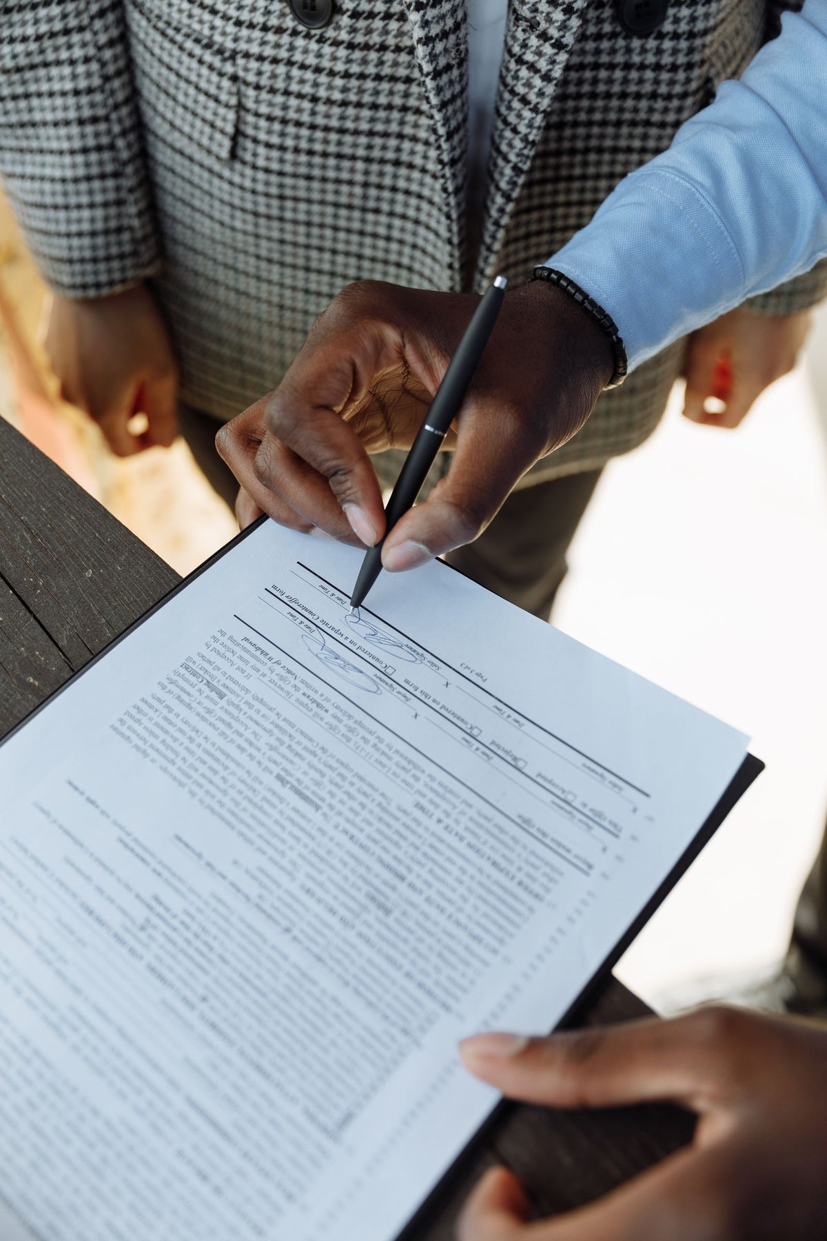 Close-up of a hand signing a business contract with a pen on a desk