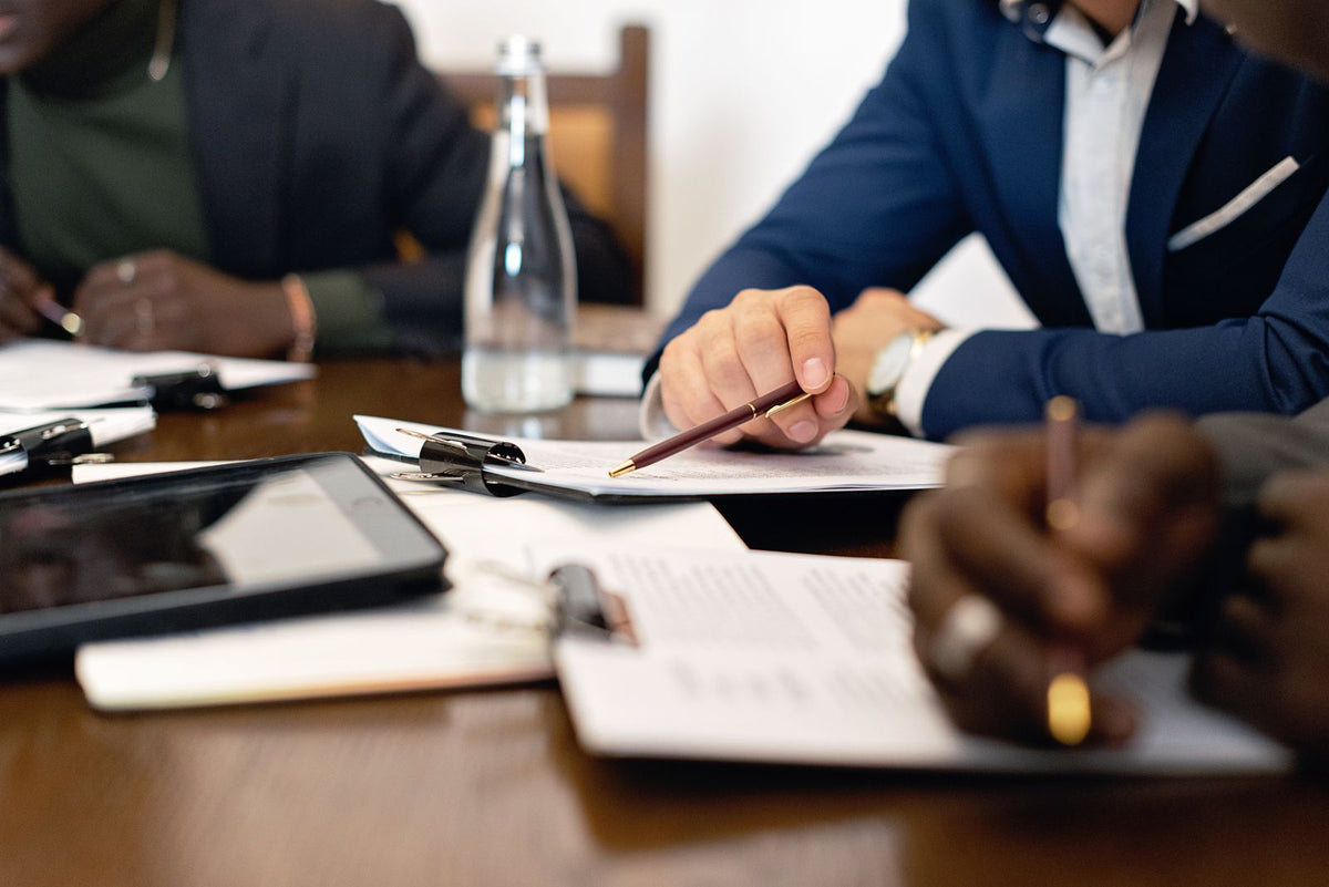 Close-up of a hand holding a pen over financing documents during a business meeting