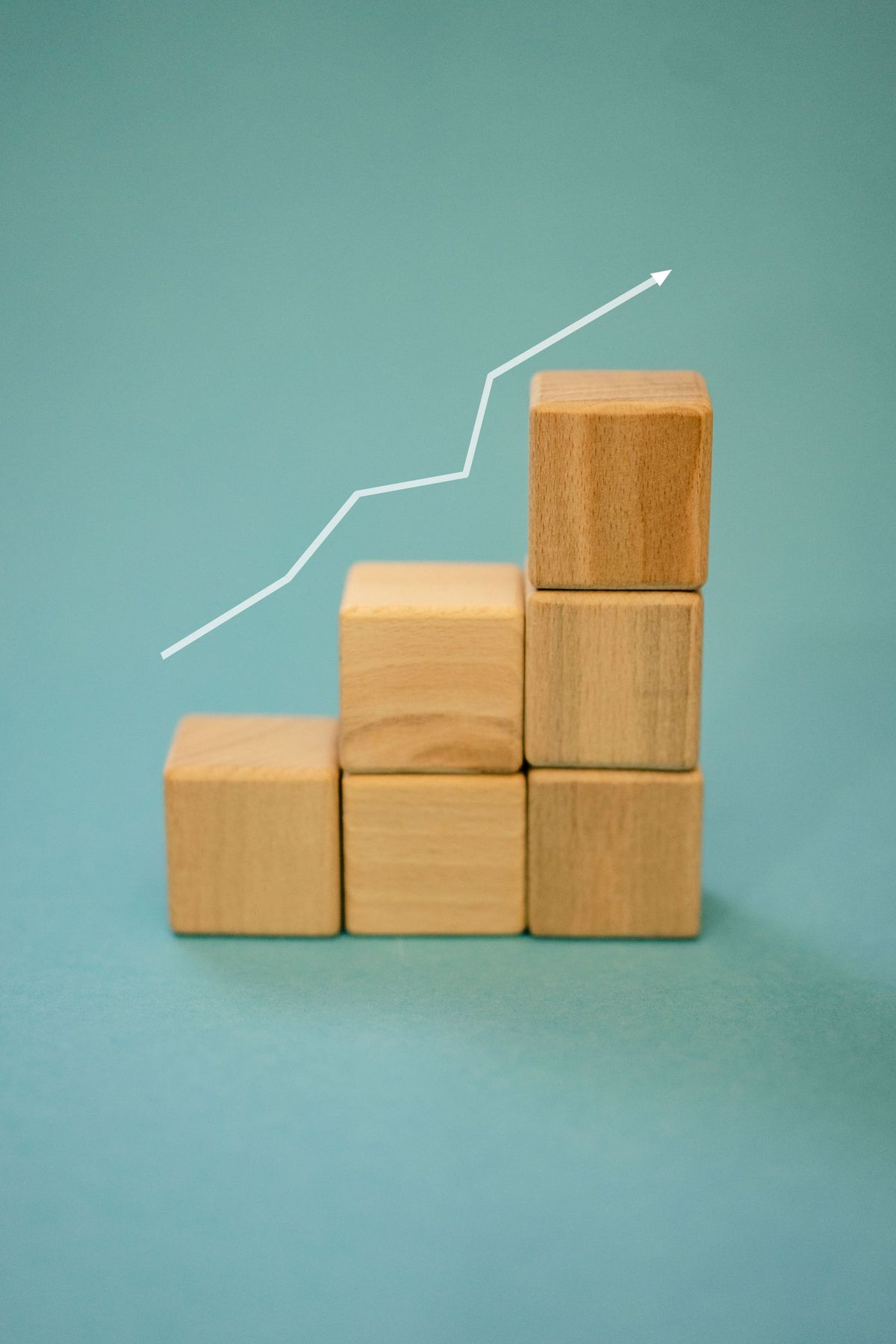 Wooden blocks arranged as a staircase with an upward arrow, symbolising startup growth from seed to Series A