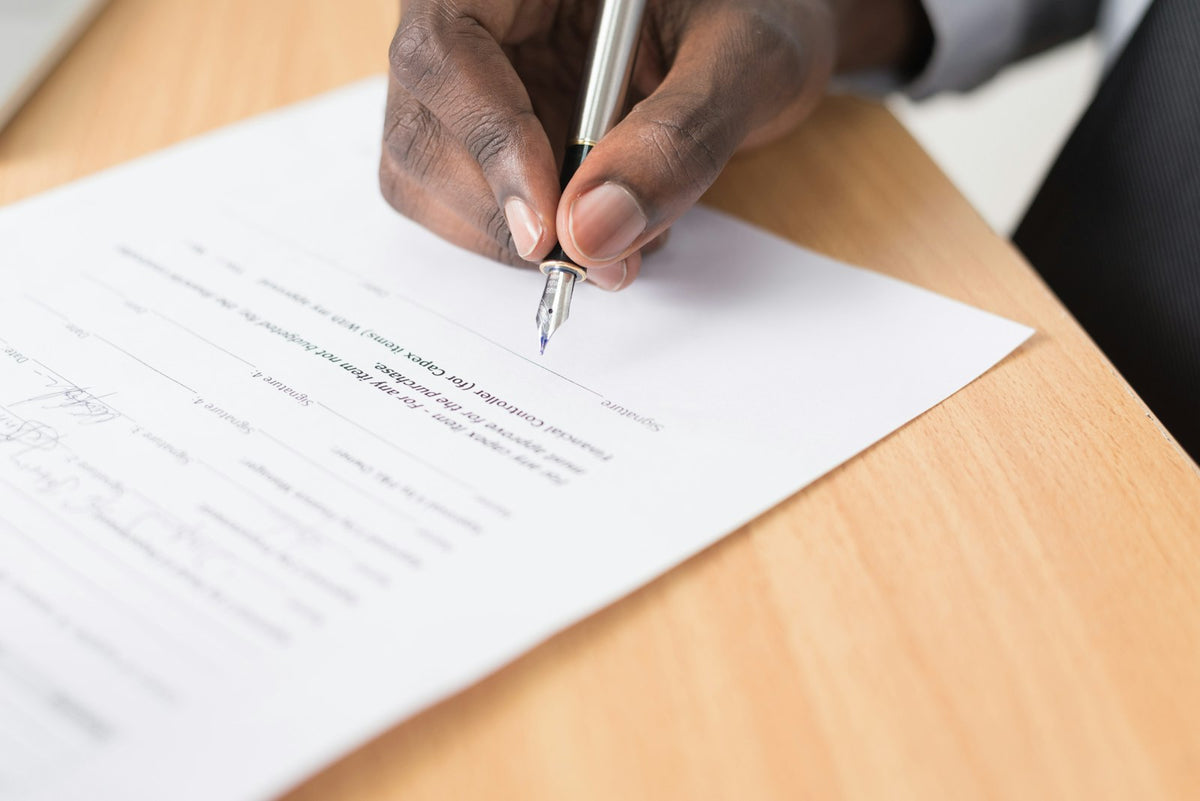 Close-up of a hand signing an employment contract on a desk
