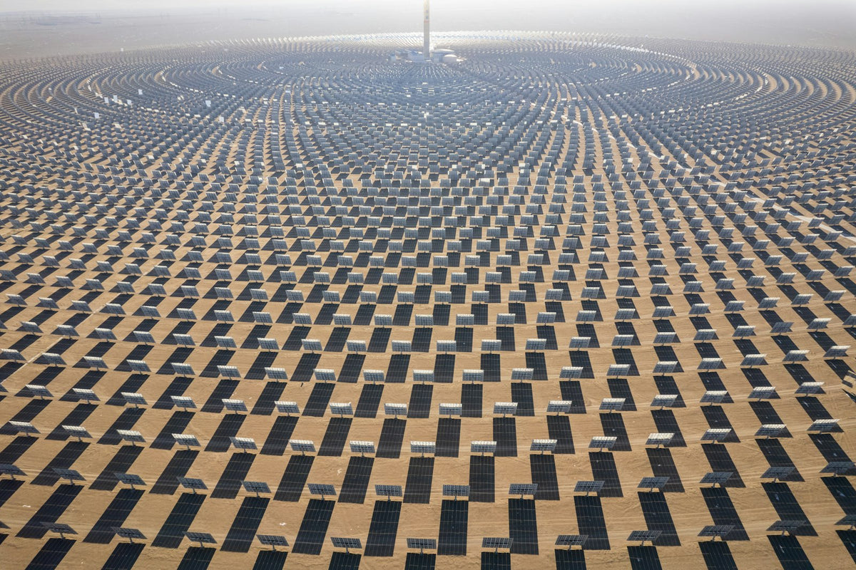 Large array of solar energy panels stretching across a desert landscape