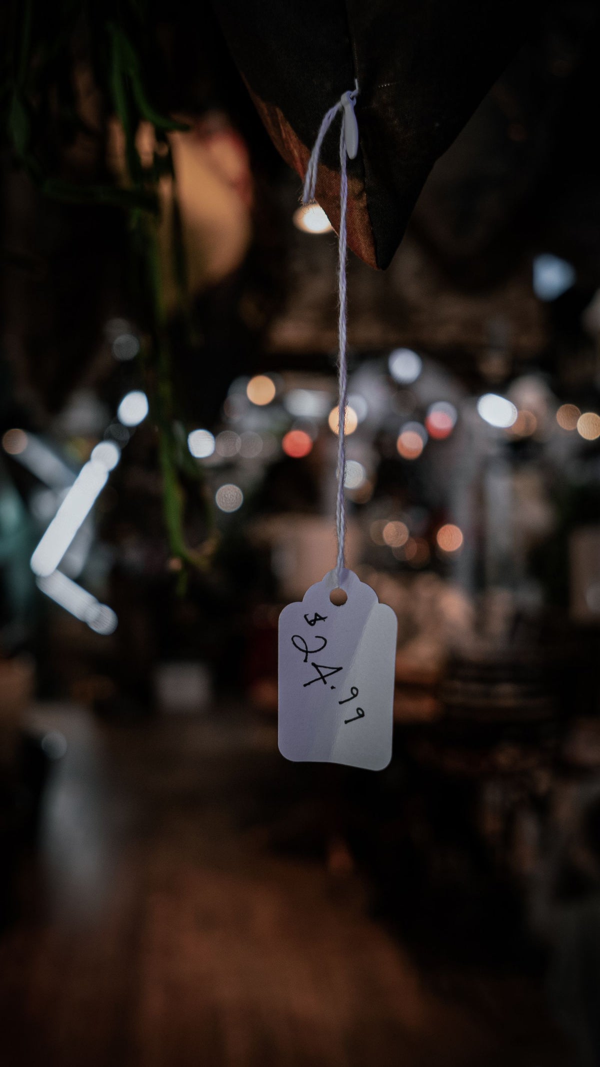 Close-up of a blank price tag hanging on a string against a softly lit background