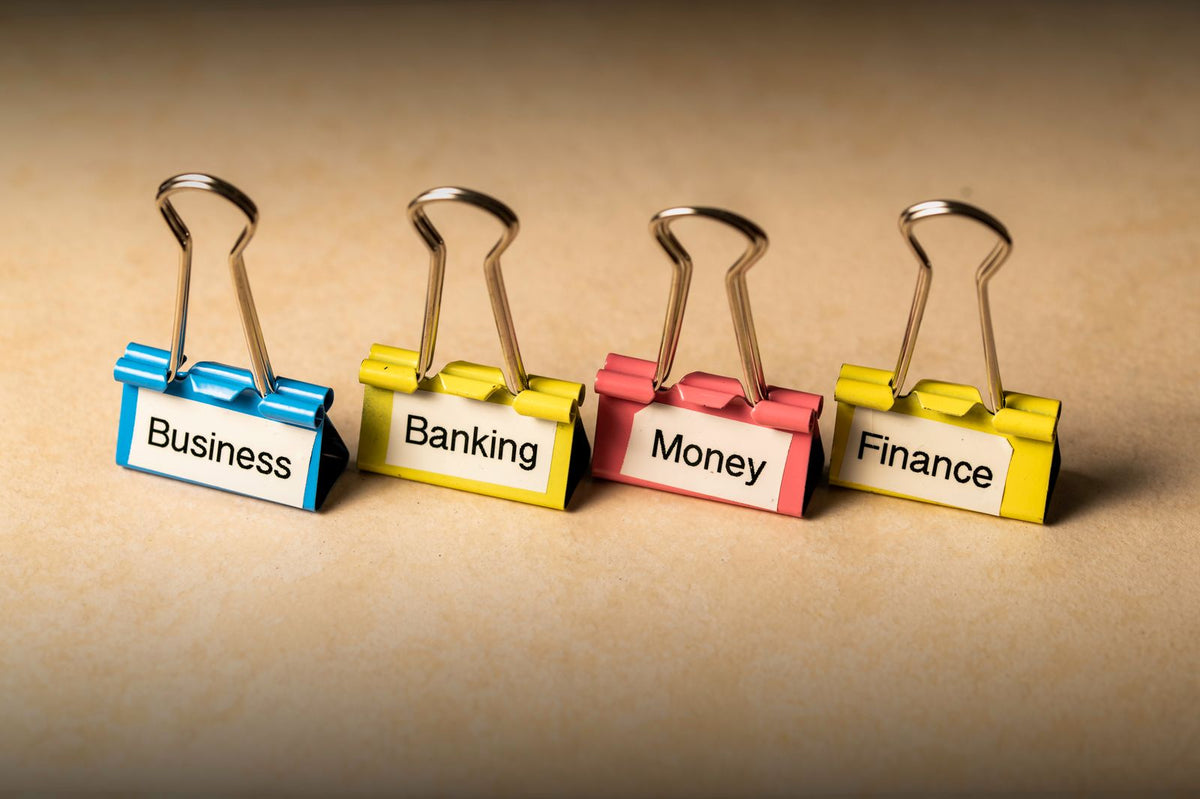 Close-up of binder clips labelled business, banking, money and finance, representing the documents needed to open a business bank account