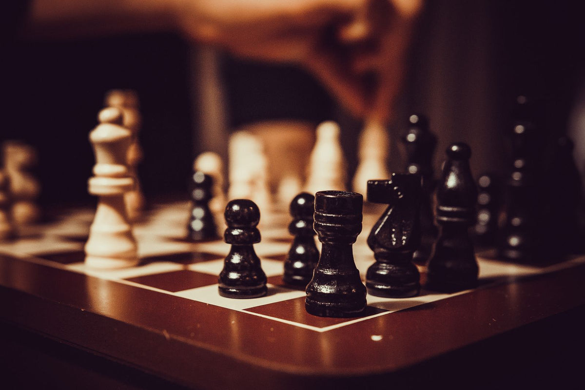 Black and white chess pieces mid-game on a wooden chessboard, symbolising deal strategy and planning an exit