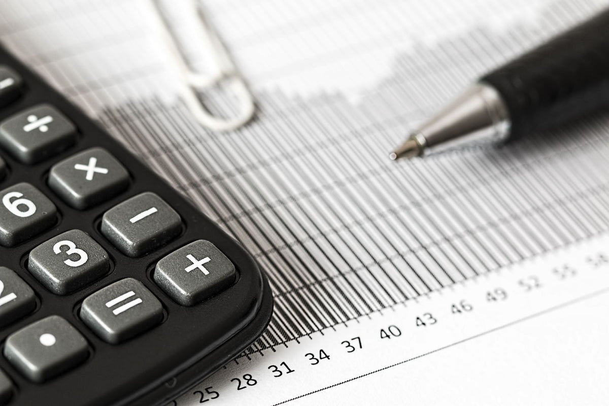Calculator and pen resting on a printed bar chart, representing startup financial metrics