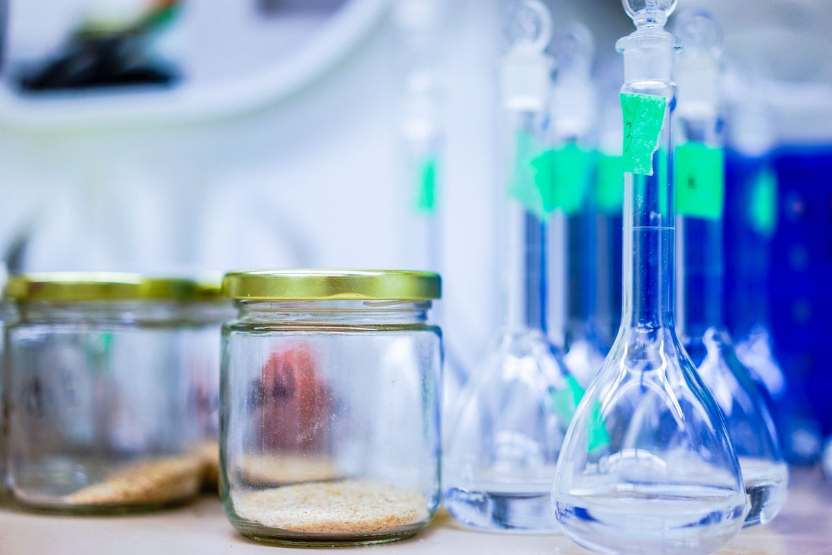 Laboratory glassware and sample jars on a research bench, representing early-stage R&D