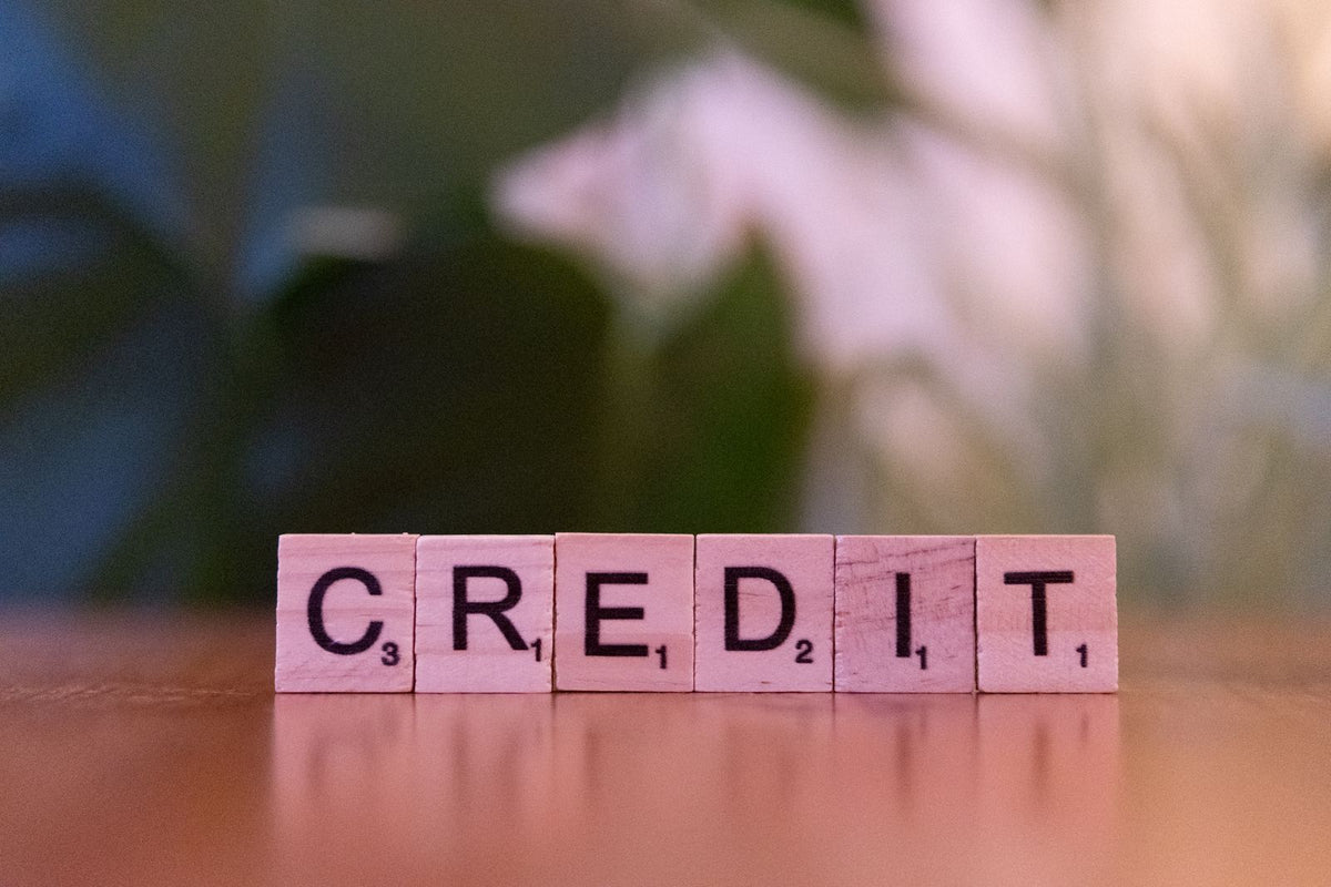 Wooden blocks spelling the word credit on a table against a blurred green background