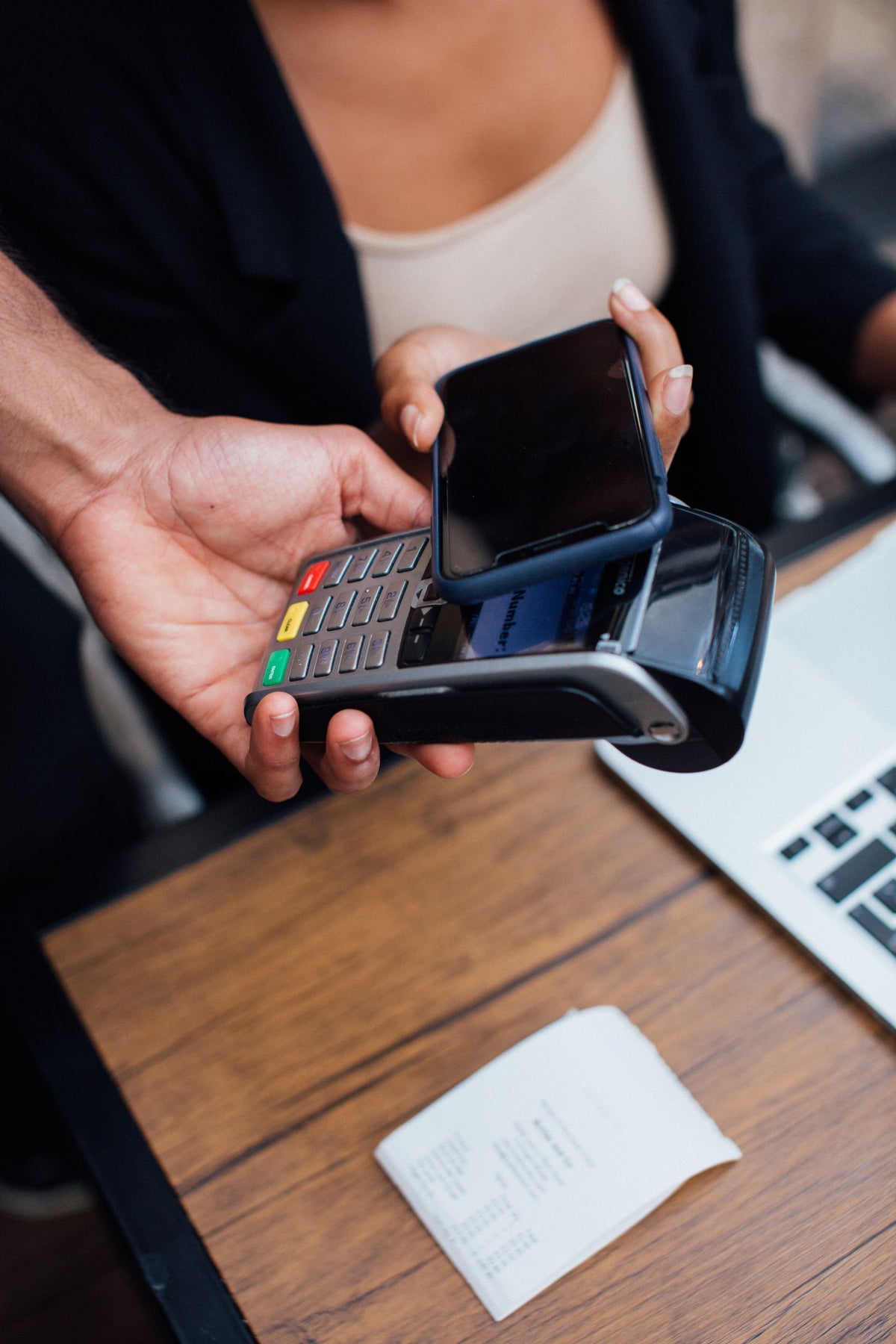 Close-up of a customer tapping a smartphone on a payment terminal to make a contactless payment