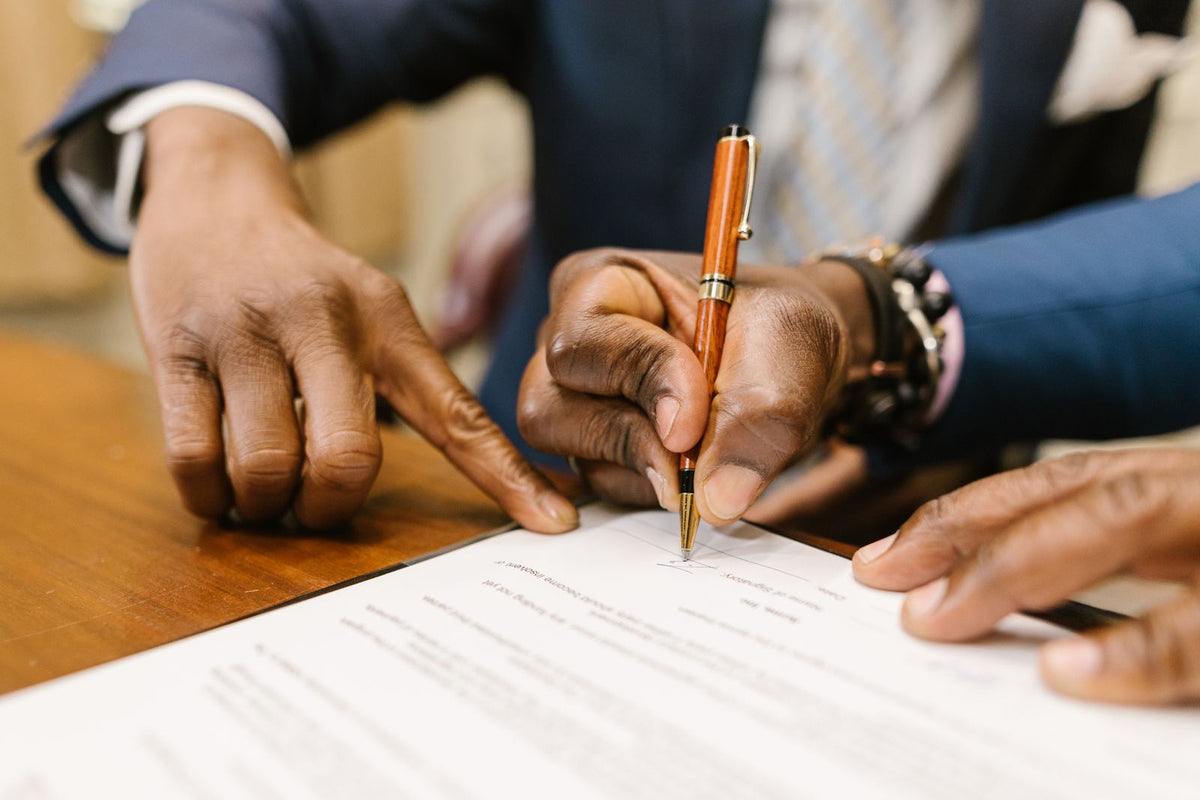 Close-up of a hand signing an investment agreement at a desk