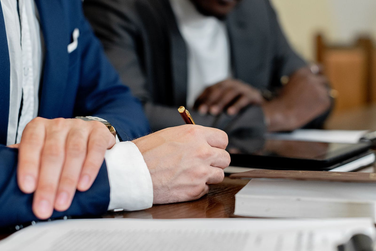 Close-up of hands reviewing and signing documents at a business meeting table