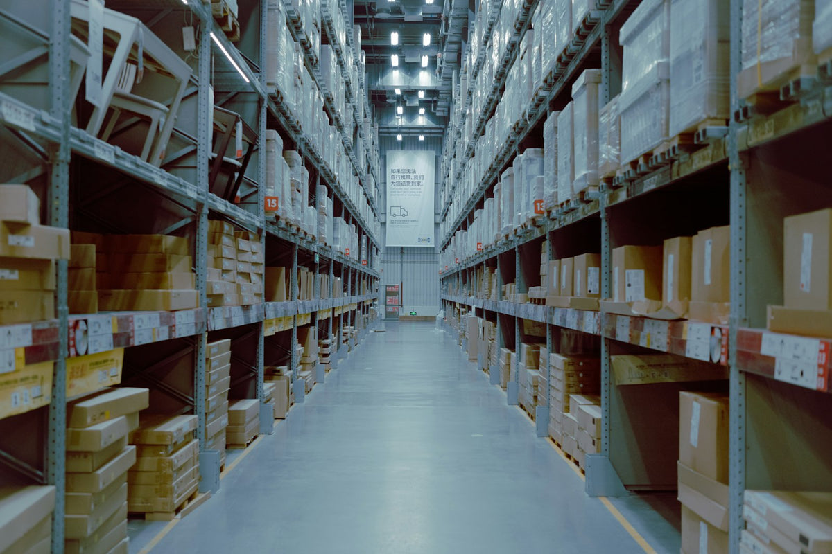 A large warehouse with rows of stocked shelves, representing inventory and supply-chain planning for SMEs